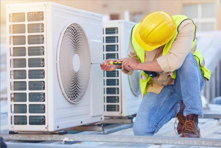 Technician working on a rooftop air conditioning unit with gauges
